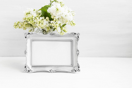 Vintage silver photo frame with lilac flowers on white still life boardの写真素材
