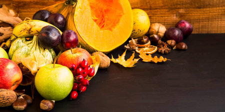 Fall fruits and vegetables harvesting on wooden tray, pumpkins, apples, plums, walnuts and chestnuts, fall decoration on wooden backgroundの写真素材
