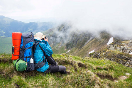 Mountain photographer and hiker with backpack and equipment outdoor on mountain peak