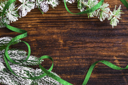 Christmas frame with fir tree branches with snow and ribbon on wooden board, top view with copy spaceの写真素材