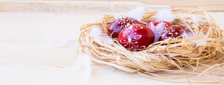 Easter eggs festive painted, decorative eggs on a straw nest with feathers