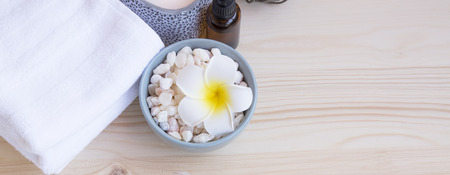 Spa still life setting with francipani flower, bath salt, towels and oil bottle on wooden backgroundの写真素材