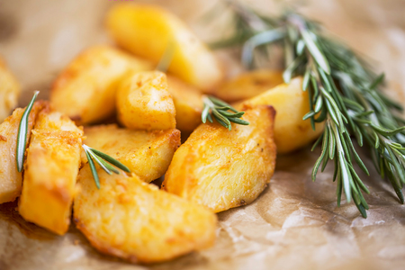 Oven roasted potatoes with rosemary herb, healthy baked potatoes seasoned with rosemary herb , closeup, selective focusの写真素材