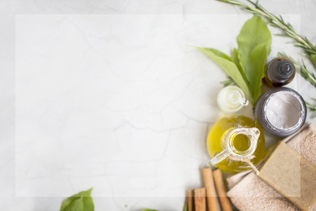 Organic skincare products flatlay with copy space, face oil bottle, olive oil and clay mask, natural soap on towel, top view on concrete backgroundの写真素材