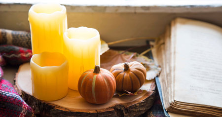 Fall decorations with candles and pumpkins with a book and blanket, cozy still life