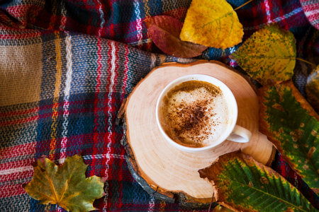Autumn coffee cup with cozy blanket  and dried leaves on a wooden tray, fall composition, top view