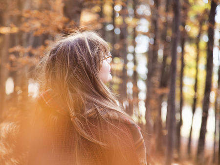 Young girl in autumn season in the park, back shot of a girl with scarf in fall outdoor, dreamy beautiful fall conceptの写真素材