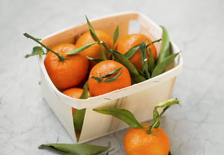 Fresh mandarines with leaves in a basket, fresh citrus fruitsの写真素材