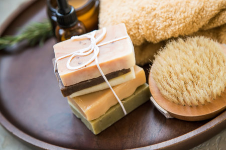 Bunch of natural soaps in wooden plate, natural spa and skincare ingredients with body brush, oil,...
