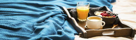 Bed breakfast with glass of orange juice and a bowl of oatmeal with fresh berries, banana and almonds, healthy morning breakfast in wooden trayの写真素材