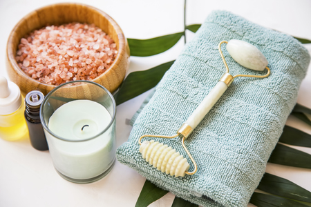 Spa still life with bath salt , jade roller, candle, towel and green leaf plant, spa and wellness settingの写真素材