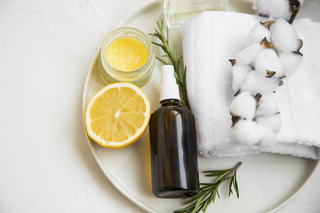 Natural organic spa ingredients with lemon, rosemary branches, balm jar, face mist spray bottle, cotton towel with cotton buds の写真素材