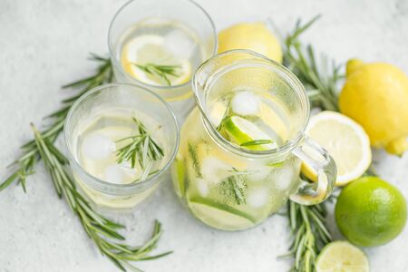 Lemonade juice with lime, lemons and rosemary herb, fresh summer ice drink, detox ifused water , lemon and lime juice with slices and ice cubes with pitcher and glassesの写真素材