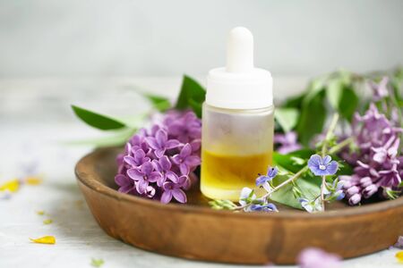 Aromatherapy oil bottle with flowers and green leaves, botanical natural beauty ingredientsの写真素材