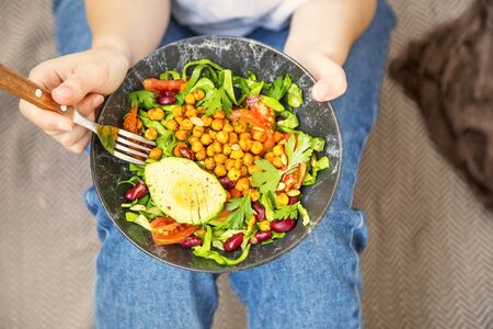Clean eating, vegan healthy salad bowl , top view of woman holding salad bowl, plant based healthy diet with greens, salad, chickpeas and vegetablesの写真素材