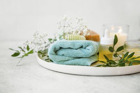 Spa still life set with towel, green leaves, oils and candle, clean beauty concept with skincare productsの写真素材