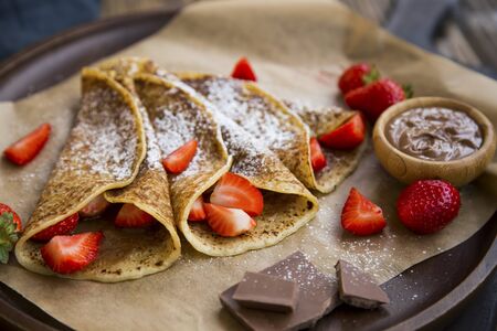 French crepes with chocolate spread and strawberries, tasty sweet dessert filled with chocolate cream and fresh strawberries fruitsの写真素材