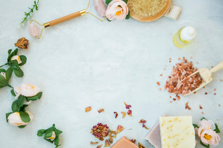 Spa still life frame with natural beauty products, bath salt, roses, natural soap, oil bottle, quartz face roller with copy spaceの写真素材