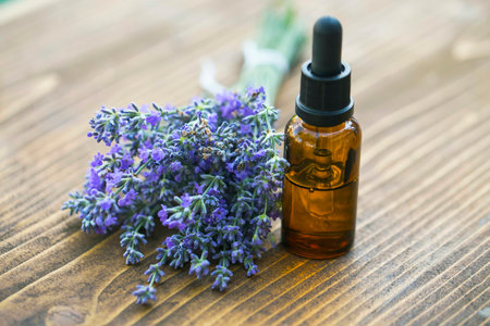 Glass bottle of Lavender essential oil with fresh lavender flowers on wooden table, aromatherapy spa massage concept. Lavendula oleumの写真素材