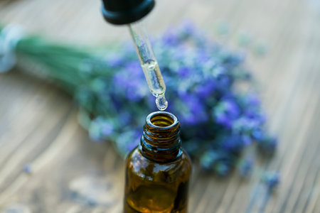 Glass bottle of Lavender essential oil with fresh lavender flowers on wooden table, aromatherapy spa massage concept. Lavendula oleumの写真素材