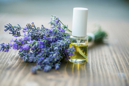Glass bottle of Lavender essential oil with fresh lavender flowers on wooden table, aromatherapy spa massage concept. Lavendula oleumの写真素材