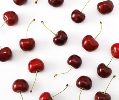 A bunch of ripe cherries with peduncles lies on a white background. Large collection of fresh red...