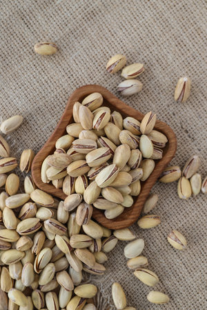 fried pistachios lie in a wooden menagerie scattered around on a wooden table and burlap without...