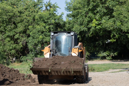 yellow excavator collects earth in a big pile without peopleの写真素材