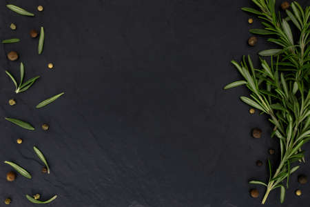 rosemary sprigs and allspice seeds are laid out on a stone board image food products photoの写真素材