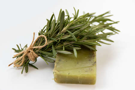 a piece of handmade green soap lies next to a bunch of rosemary without people natural cosmeticsの写真素材