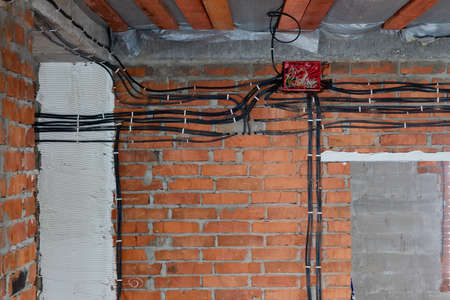 construction of a new cottage, a lot of electrical cables are assembled in a red junction box under the ceiling of the room without peopleの写真素材