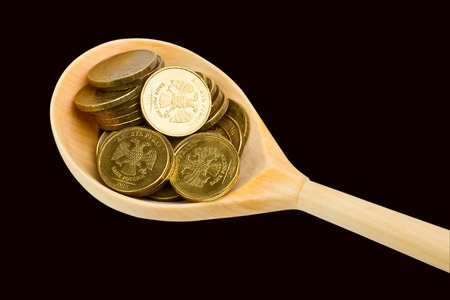 Wooden spoon with coins on a black backgroundの写真素材