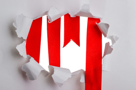 Red ribbon in the frame of torn paper on a white backgroundの写真素材