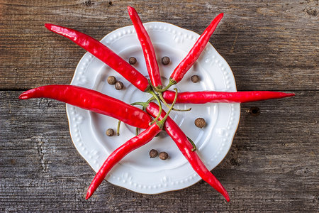 Red hot chili peppers on a white plate. against the background of a wooden surfaceの写真素材