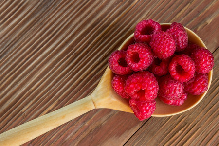 Ripe raspberries in a wooden spoon on the table. Can be used as background
