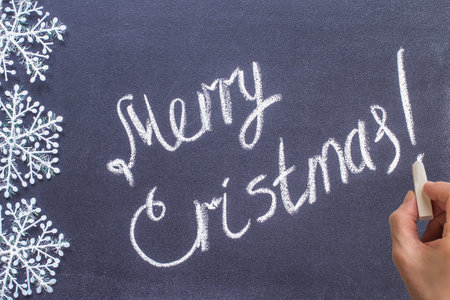 Woman hand writing Merry Christmas on chalkboard. written on a blackboard
