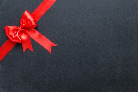 Red ribbon with a bow on a black board. Celebratory background with copy spaceの写真素材