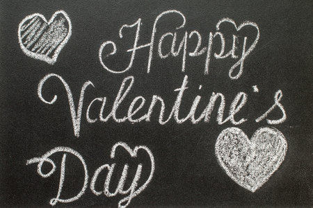 Happy Valentine's Day written in white chalk on a black chalkboardの写真素材