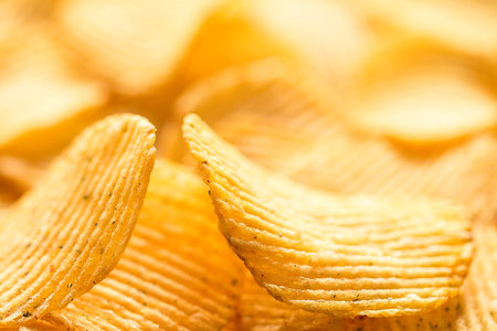 Yellow salted potato chips as background, closeup. Chips texture studio photo