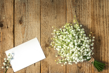 Lilies of the valley in a bouquet on a wooden old table and place for your textの写真素材
