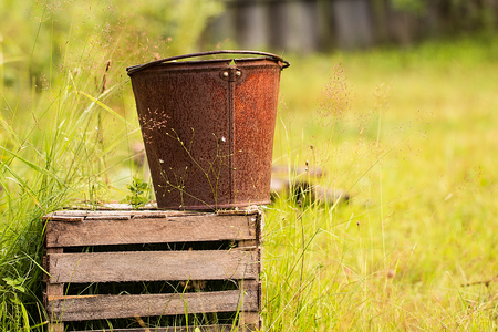 an old iron bucket in the garden at wooden palletの写真素材