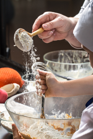 Little girl kneading dough for cookies with the assistance of her mother. Mother and daughter making cookies for Christmas.の写真素材