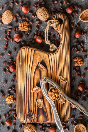 Old cutting board  and different nuts on stone table.の写真素材