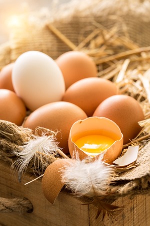 bunch of fresh brown eggs and some straw in a wooden crate の写真素材