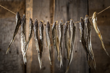 dried fish hanging on a line,  on a rope on old  wooden background