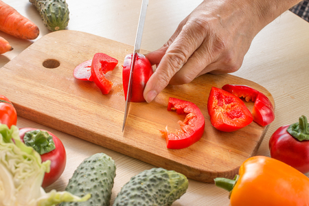 Closeup of hands of chef cook cutting vegetables on wooden table の写真素材