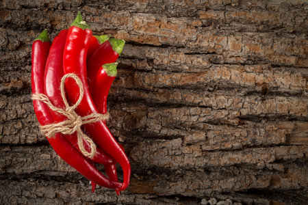 Red hot chili peppers tied with rope on wooden background.  culinary background. Top view with copy...