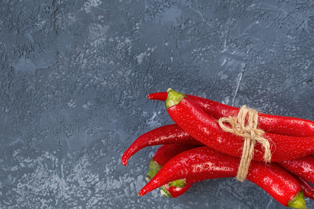 Red hot chili peppers tied with rope over gray stone background. Top view with copy space.  culinary background.の写真素材