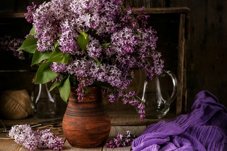 Bouquet of lilac flowers in a ceramic pot on old  tableの写真素材