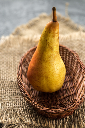 one ripe pear in wicker basket on rustic  table.  Fruit background. Fresh organic pears on old wood. Pear autumn harvestの写真素材